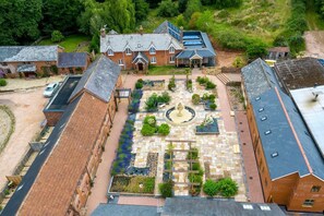 Luftaufnahme eines Innenhofs mit einer zentralen Fontäne, umgeben von Ziegelgebäuden mit Solaranlagen.