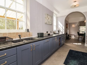 A modern kitchen with a large window, dark blue cabinets, and a black countertop. - Buckland House and Annex, Taunton (Taunton)
