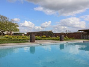 A swimming pool with a brick wall and greenery in the background. - Buckland House and Annex, Taunton (Taunton)