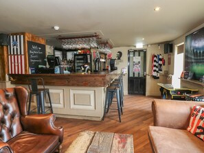 A bar area with a wooden counter, stools, and a barista station. There are leather chairs and a table with a patterned table runner. - Spacious Cottage Number 9, Brandon, County Durham (Durham)