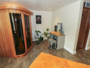 Une pièce comprenant une armoire en bois, un bureau avec un miroir, une chaise et une plante en pot.