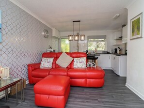 Un salon moderne avec un canapé en cuir rouge, une table basse en verre et un coin repas comprenant une table et des chaises en bois.