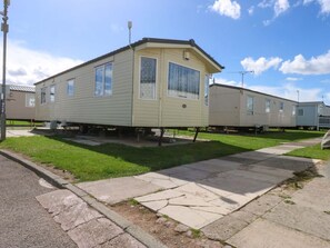 A single-story mobile home with a flat roof, a front porch, and a small attached garage. - Hideaway Lodge, Abergele (Abergele)
