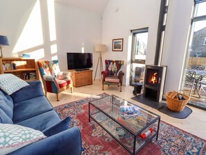 A living room with a sofa, a glass coffee table, a fireplace, a television, and a bookshelf.