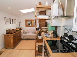 Una cocina compacta con muebles de madera, horno empotrado y encimera con diversos utensilios de cocina.