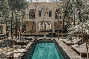 Un espace piscine avec des chaises longues et un bâtiment en arrière-plan.