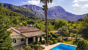 Una villa con piscina, rodeada de exuberante vegetación y montañas.