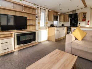 A compact living space with a flat-screen TV, a microwave, a coffee maker, a sofa, and a wooden coffee table. - The Drift, Skipsea - A Coastal Retreat (Driffield)