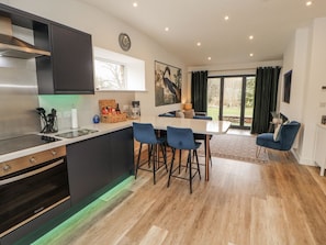 A modern kitchen with a central island, bar stools, and a dining table.