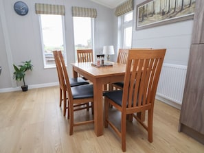 Un comedor con una mesa y sillas de madera, un reloj en la pared y una ventana con vistas.