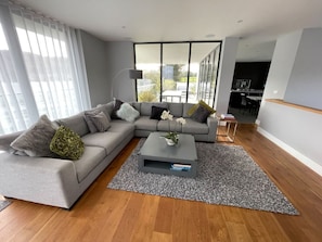 A modern living room with a grey sofa, a coffee table, and a view of the outdoors.