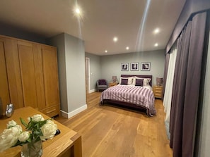 A bedroom with a bed, wooden wardrobe, bedside tables, and a nightstand.