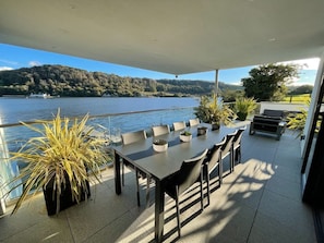 A covered outdoor dining area with a view of a lake and hills.