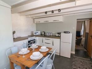 Eine kleine Küche mit weißen Schränken, einer Mikrowelle, einem Herd und einem Kühlschrank.