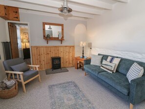 Ein gemütliches Wohnzimmer mit einem grünen Sofa, einem Holzstuhl, einem kleinen Tisch mit Lampe und einem Kamin.