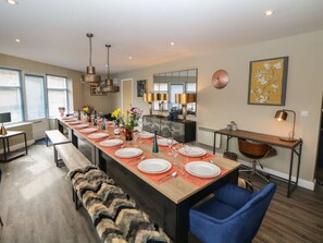 A modern dining area with a long table set for six, a bench, and a blue chair. - Chatsworth, Two Dales (Matlock)