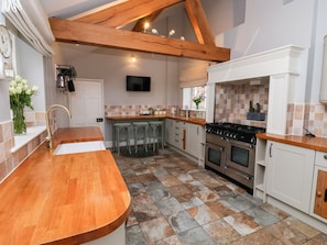 A kitchen with a wooden countertop, a sink, a stove, and a tiled backsplash. - The Stables and West Wing (6 bed), Tadcaster (York)