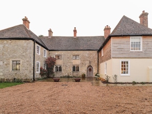 A stone building with a wooden extension, a gravel courtyard, and a door with a wreath. - Battel Hall, Hollingbourne (Maidstone)