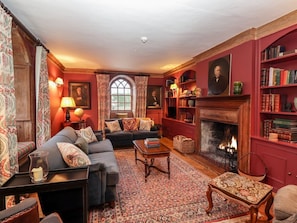 A traditional living room with a fireplace, bookshelves, and a patterned rug. - Battel Hall, Hollingbourne (Maidstone)