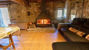 Ein rustikales Interieur mit Steinwand, Kamin, Holztisch und Ledersofa.