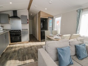 Een moderne keuken met inbouwapparatuur, een eethoek met een tafel en stoelen, en een zithoek met een bank en kussens.