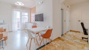 Un salon moderne comprenant un coin repas, un téléviseur à écran plat et une cuisine.