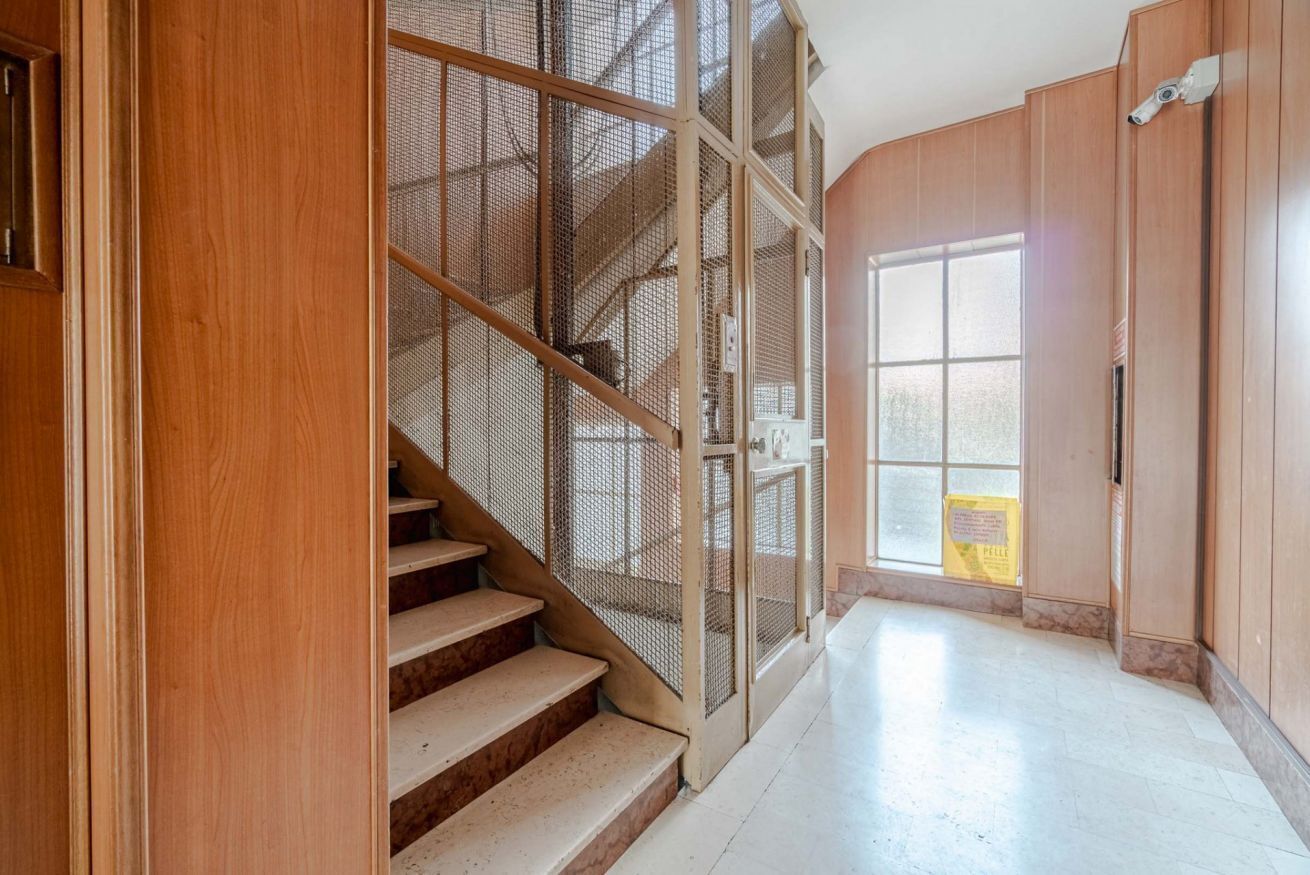 Eine Treppe mit einem Drahtgittergeländer, Holzwänden und einem großen Fenster.