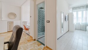 Vue intérieure d’un appartement moderne comprenant un coin repas, une douche en verre et un espace de vie.