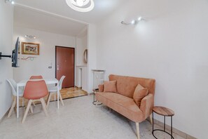 A modern living room with a sofa, a dining table with chairs, a small side table, and a door leading to another room. - GuestHost - A bright and welcoming 57 square meters apartment, perfect for three people, located on the fourth floor of a building with an elevator (NOT accessible to disabled guests).The property enjoys an excellent location: the Bengasi metro station i (Turin)