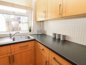 Eine Küche mit Holzausstattung, einer schwarzen Arbeitsplatte, einem Fenster und einem Toaster.