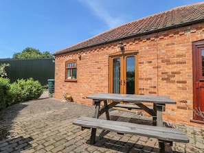 A brick building with a tiled roof, a wooden door, and a picnic table in front. - Charming Kingfisher Retreat in Louth (Louth)
