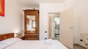 Habitación de hotel con cama, armario de madera, espejo y puerta que da a otra habitación.