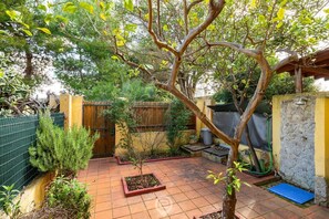 Ein Innenhof mit Fliesenboden, einem Baum und einer kleinen Gartenanlage.