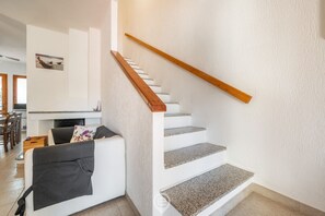 Eine Treppe mit hölzernen Geländern, einer weißen Wand und einem Wohnbereich mit Sofa und Kamin.
