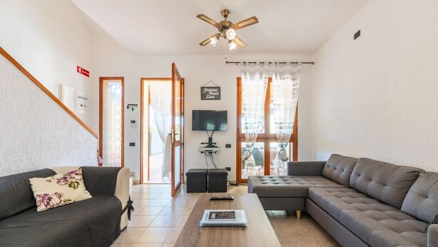 Una sala de estar con un sofá, una mesa de centro, un televisor y un ventilador de techo.