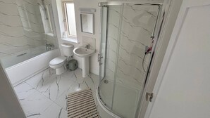 A bathroom with a bathtub, toilet, sink, and a glass-enclosed shower.