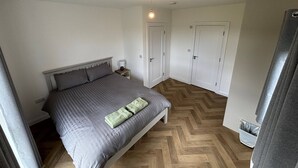 A bedroom with a bed, nightstand, two doors, and a light fixture.