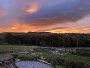 A rural landscape with rolling hills, a stone wall, and a wooden bench. - The Farmhouse, in East Morton. (Keighley)