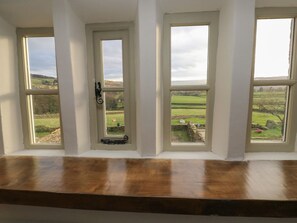A room with four windows, each with a view of a green landscape. - The Farmhouse, in East Morton. (Keighley)