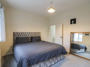 A bedroom with a tufted headboard, a large mirror, and a neutral color scheme. - Peckhamsbest Suite, Southwark, London (London)