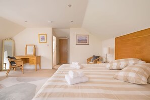 Ein Hotelzimmer mit Bett, Schreibtisch, Stuhl, Spiegel, Tür und einem Bild an der Wand.