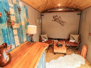 Ein gemütliches Zimmer mit Holztisch, Stühlen, einer Lampe und dekorativer Wandgestaltung.