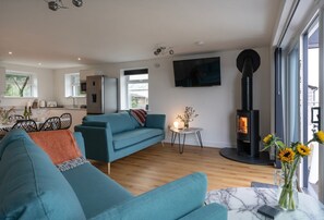 Ein modernes Wohnzimmer mit einer Couch, einem Kamin, einem Essbereich und einem Fernseher.
