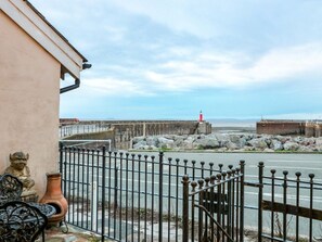 A coastal view with a red lighthouse, a stone wall, and a metal fence. - Sammy Hakes Cottage, Watchet (Watchet)
