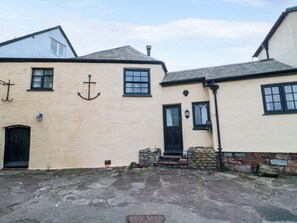 A building with a beige exterior, black windows, and a black door. - Sammy Hakes Cottage, Watchet (Watchet)