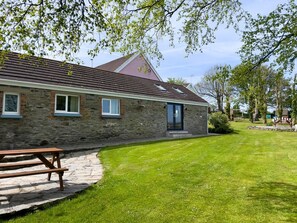 A stone building with a red roof, a paved patio, and a well-maintained lawn.