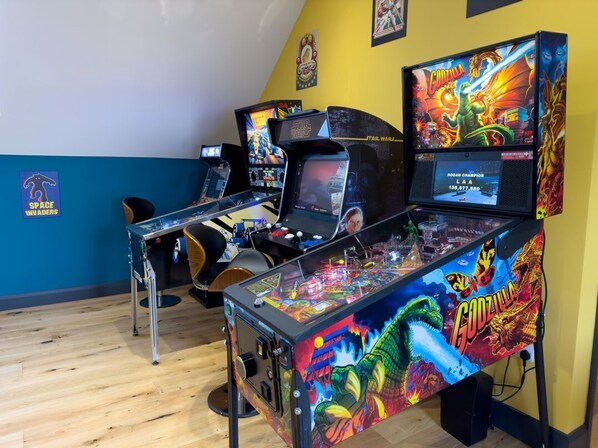 A room with arcade machines, including Star Wars and Godzilla themed games, and a Space Invaders machine.