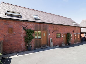 A brick building with a sloped roof, wooden doors, and a small window. - Woodpecker Cottage, Llangollen (Llangollen)