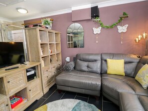 A living room with a sofa, TV, wooden cabinet, and decorative wall elements. - Pentre Country Studio, Chirk (Chirk)
