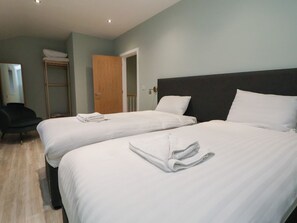 Ein Hotelzimmer mit zwei Betten, einem Kleiderschrank, einem Spiegel und einem Sessel.